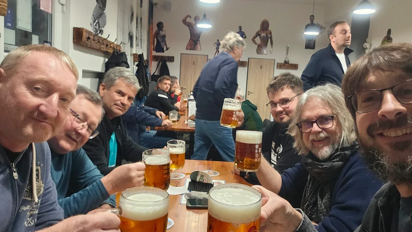 Parta hostů s půllitry u společného stolu ve Sport Pubu